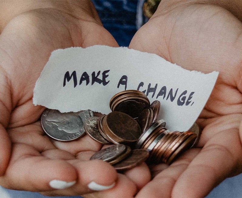 hands holding coins and paper with words make a change