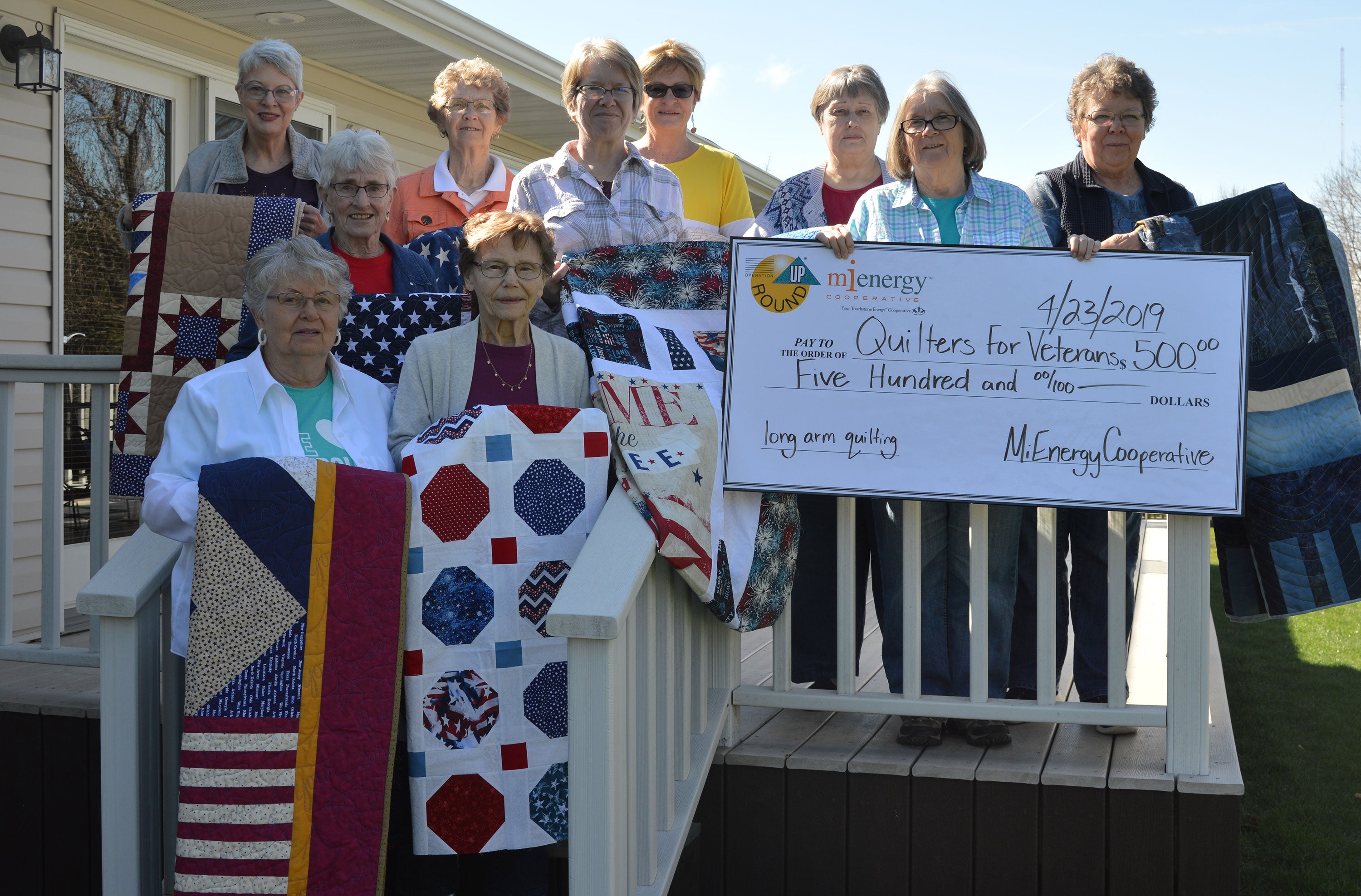 photo showing women from Quilters for Veterans holding quilts