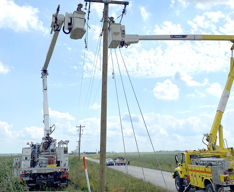 line trucks with workers in buckets fixing power lines